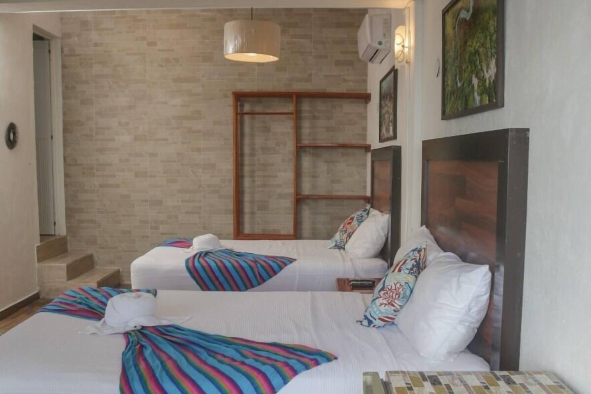 Ein Hotelzimmer mit zwei Betten, einem Holzkopfteil, einem Fliesenboden und einer Hängelampe.