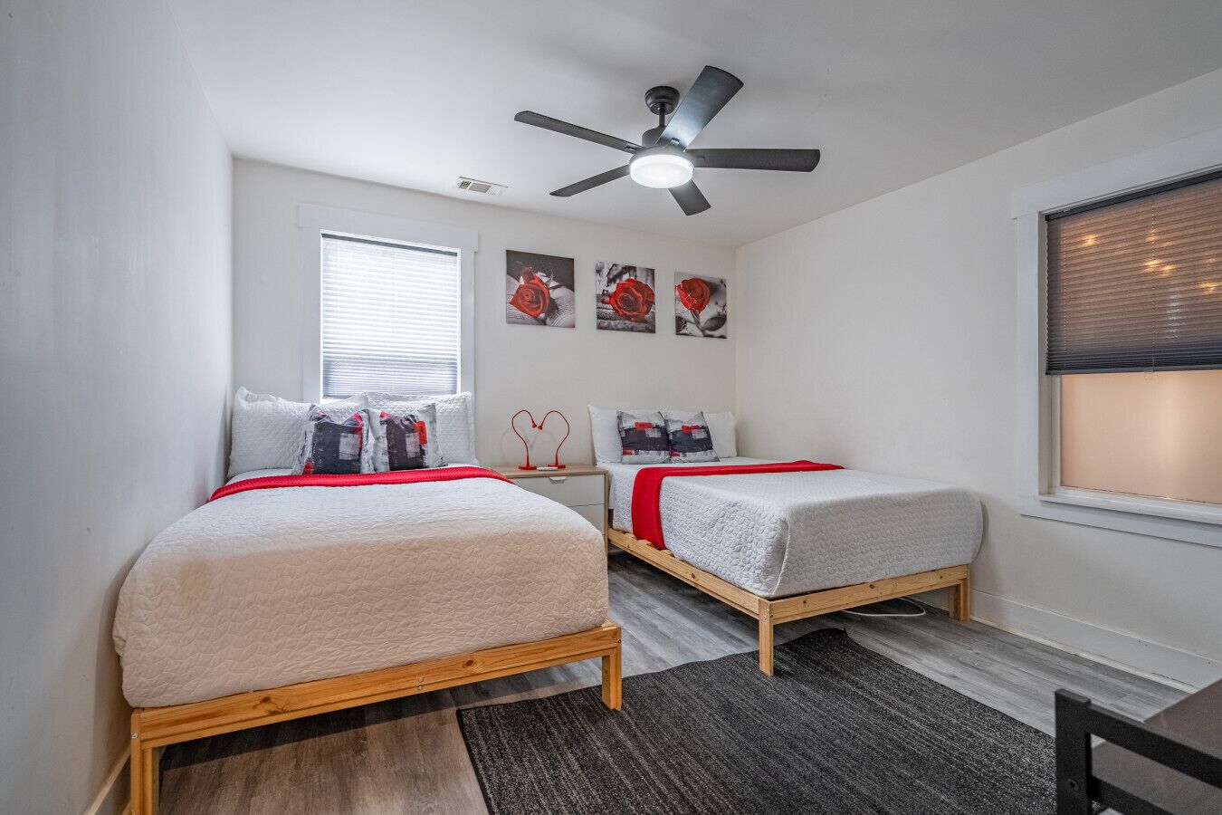 Ein Schlafzimmer mit zwei Betten, einem Deckenventilator und Kunstwerken an der Wand.