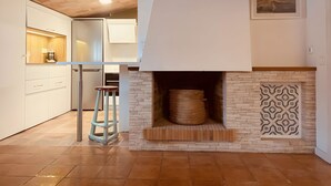 Une cuisine moderne avec des armoires blanches, un plafond en bois et une cheminée ornée de carreaux décoratifs.