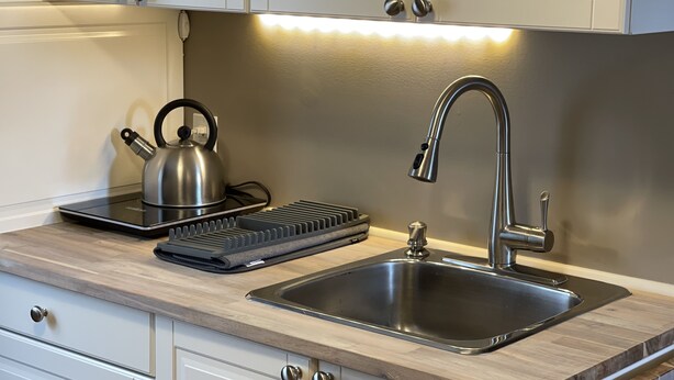 Een moderne keuken met een waterkoker, broodrooster en een roestvrijstalen spoelbak.
