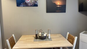 Een eethoek met een houten tafel, twee stoelen, een schaal met snacks en twee zoutstrooiers.