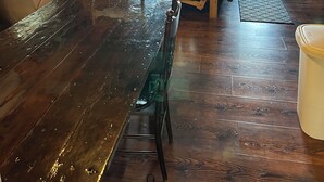 L’intérieur d’un chalet en bois comprend une table à manger, des chaises, un téléviseur et une fenêtre avec des rideaux.