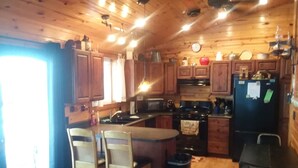 Une cuisine chaleureuse, aménagée dans un style rustique, avec des meubles en bois, un îlot central doté de chaises, un réfrigérateur et une cuisinière.