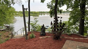 Un espace aménagé avec une terrasse en bois, un paillis et des sculptures métalliques.