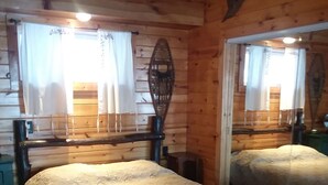 Une chambre dans un chalet en bois, avec deux lits, un plafond en bois et un grand miroir.