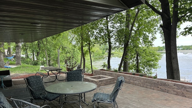 Une terrasse extérieure avec une table et des chaises, donnant sur un lac.
