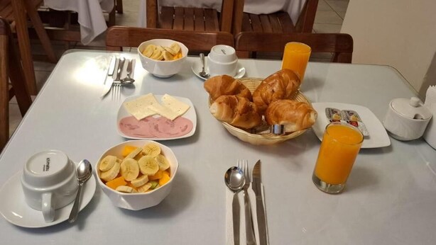 A breakfast table with croissants, a bowl of sliced bananas, a plate of cheese, a cup of coffee, and a glass of orange juice. - Hotel Kuntur House (Machu Picchu)