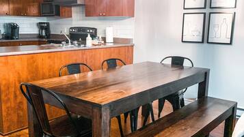 A modern kitchen with wooden cabinets, a built-in island, and a dining area with a large wooden table and chairs.