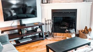 A living room with a flat-screen TV, a fireplace, a sofa, a coffee table, and a bookshelf.