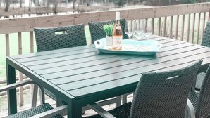 A wooden deck with a table set for a meal, featuring a bottle and wine glasses. - Golf Course Townhome with Deck, BBQ & Views – 4BR Mont Tremblant (Mont-Tremblant)