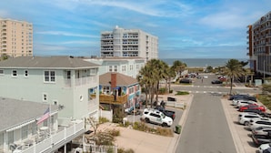 Uma área residencial costeira com edifícios altos, um estacionamento e vista para o oceano.