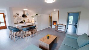 Una sala de estar moderna con un sofá, una mesa de centro y una zona de cocina con taburetes de bar.