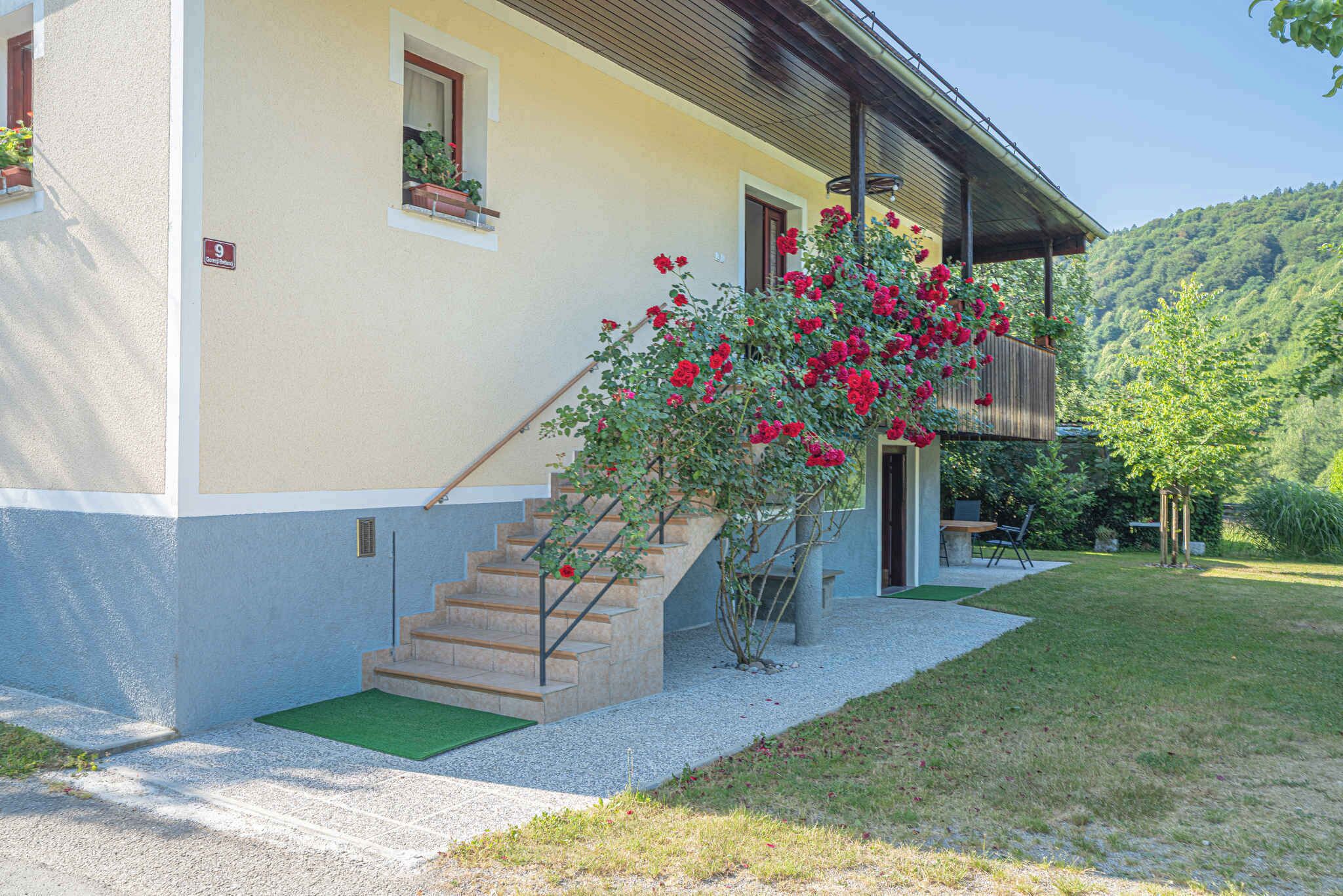A building with a staircase leading to a door, a small garden area with a green mat, and a number sign indicating the location.