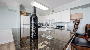 A kitchen with a granite countertop, a wine bottle, and two wine glasses.