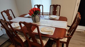 A dining table with a vase of red flowers, a placemat, and a folded napkin. - Ryan Home (Columbus)