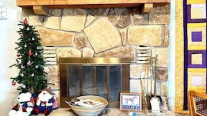 A stone fireplace with a framed picture above, a small Christmas tree, and a stable sign. - Riverfront Home w/kayaks, firepit, grill, fish 8mi Coopers 8mi Castell Gen Store (Llano)