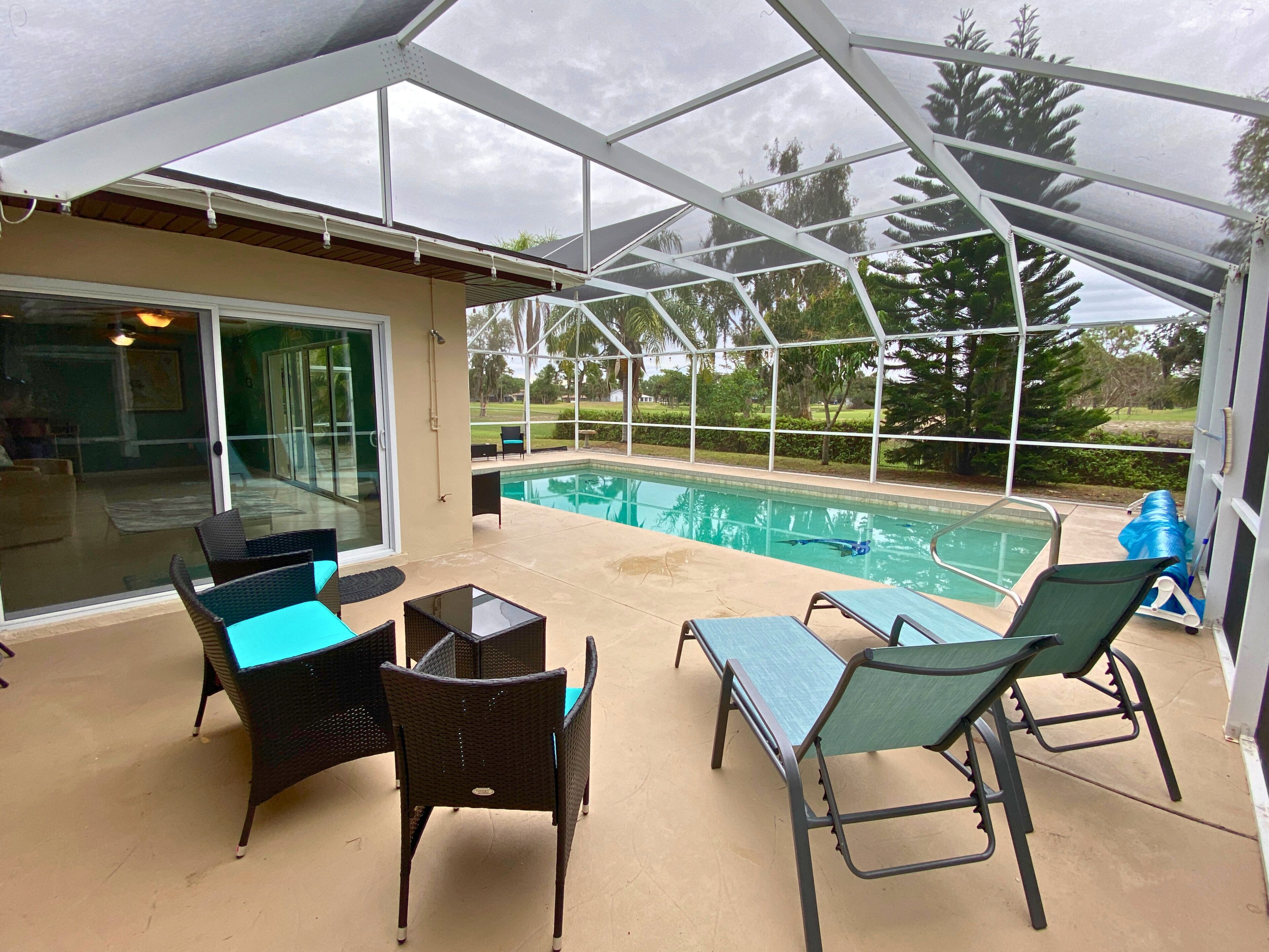 A covered patio area with a pool, outdoor furniture, and a glass door leading to an interior space.