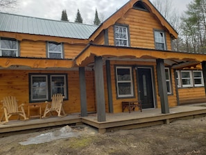 A log cabin with a porch, two windows, and a door.