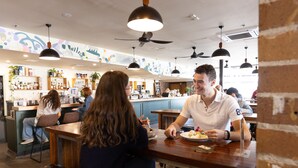 En restaurant med træborde og -stole, et barområde og en disk med diverse varer.