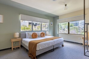 Un dormitorio moderno con una cama grande, dos mesitas de noche y vistas al exterior.