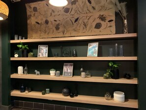 A wall with a botanical print and shelves with various items including framed pictures, plants, and decorative objects. - Roamer Brisbane (Brisbane)