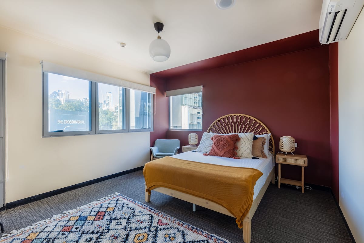 A bedroom with a bed, a window, a chair, and a small table.