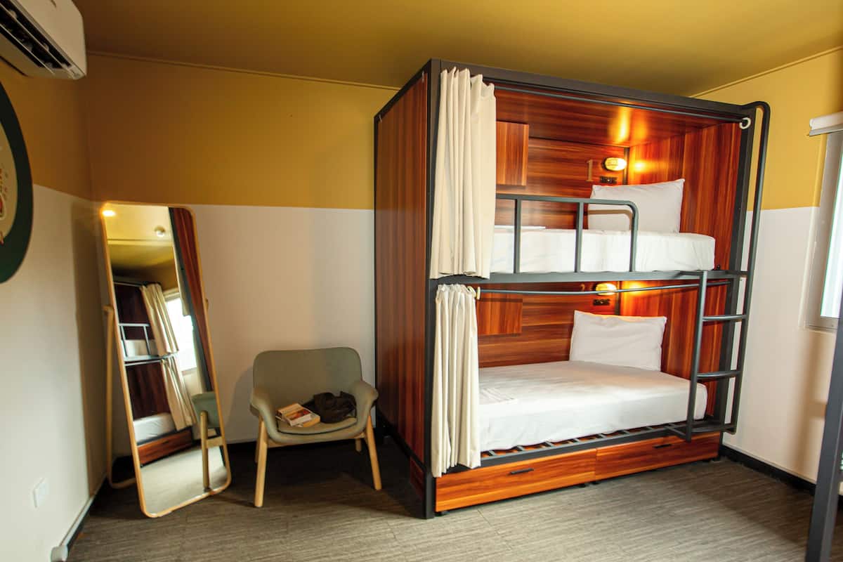 A bunk bed room with a chair and a mirror.