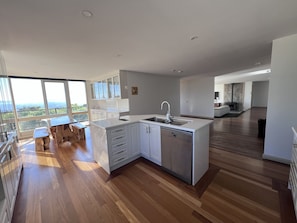 A modern kitchen with a large island, wooden flooring, and a view of the outdoors. - The Cutting Estate Mount Panorama (Mount Panorama)