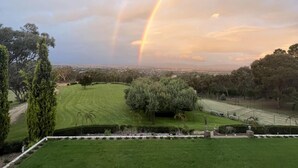 A lush green lawn with a view of a distant cityscape and a rainbow in the sky. - The Cutting Estate Mount Panorama (Mount Panorama)