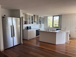 A modern kitchen with a central island, stainless steel appliances, and white cabinetry. - The Cutting Estate Mount Panorama (Mount Panorama)