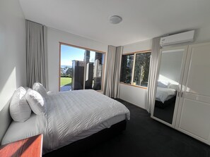 A bedroom with a bed, a wardrobe, and a large window offering a view of the outdoors. - The Cutting Estate Mount Panorama (Mount Panorama)