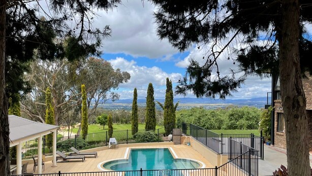 A swimming pool with a view of the countryside, surrounded by a fence and trees. - The Cutting Estate Mount Panorama (Mount Panorama)