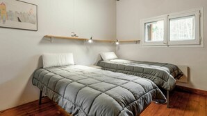 A bedroom with two beds, wooden flooring, a ceiling with exposed beams, a window with a view, and a wall-mounted shelf with lights. - Stunning private villa for 8 people with WIFI, TV, balcony and pets allowed (Alp)