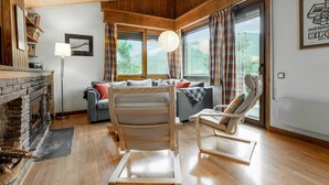 A cozy room with a fireplace, a sofa, a chair, and large windows with curtains. - Stunning private villa for 8 people with WIFI, TV, balcony and pets allowed (Alp)