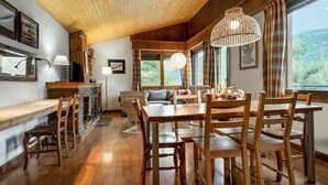 A cozy, wooden-floored dining area with a large table and chairs, a fireplace, and a view of the outdoors through large windows. - Stunning private villa for 8 people with WIFI, TV, balcony and pets allowed (Alp)