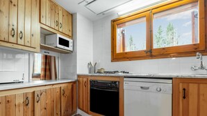 A kitchen with wooden cabinets, a microwave, stove, dishwasher, and a window with a view of trees. - Stunning private villa for 8 people with WIFI, TV, balcony and pets allowed (Alp)