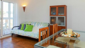 Una sala de estar con un sofá, una mesa de vidrio y un aparador.