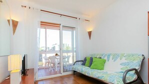 Una habitación acogedora con un sofá, un televisor y una mesa con sillas.