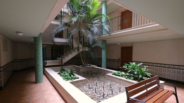 A spacious atrium with a central water feature, a wooden bench, and a staircase leading to an upper level.