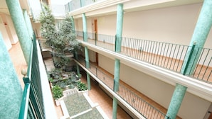 A multi-level atrium with a central garden area, multiple balconies, and a tiled floor.