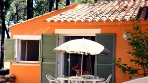 A small house with a tiled roof, a table with chairs, and a white umbrella. - Nice apartment in villa for 6 guests with pool, A/C, WIFI, TV, terrace and pets allowed (Borgo)