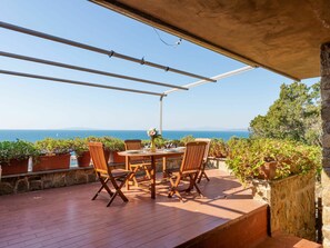 Una terraza con una mesa y sillas, con vista a un cuerpo de agua.
