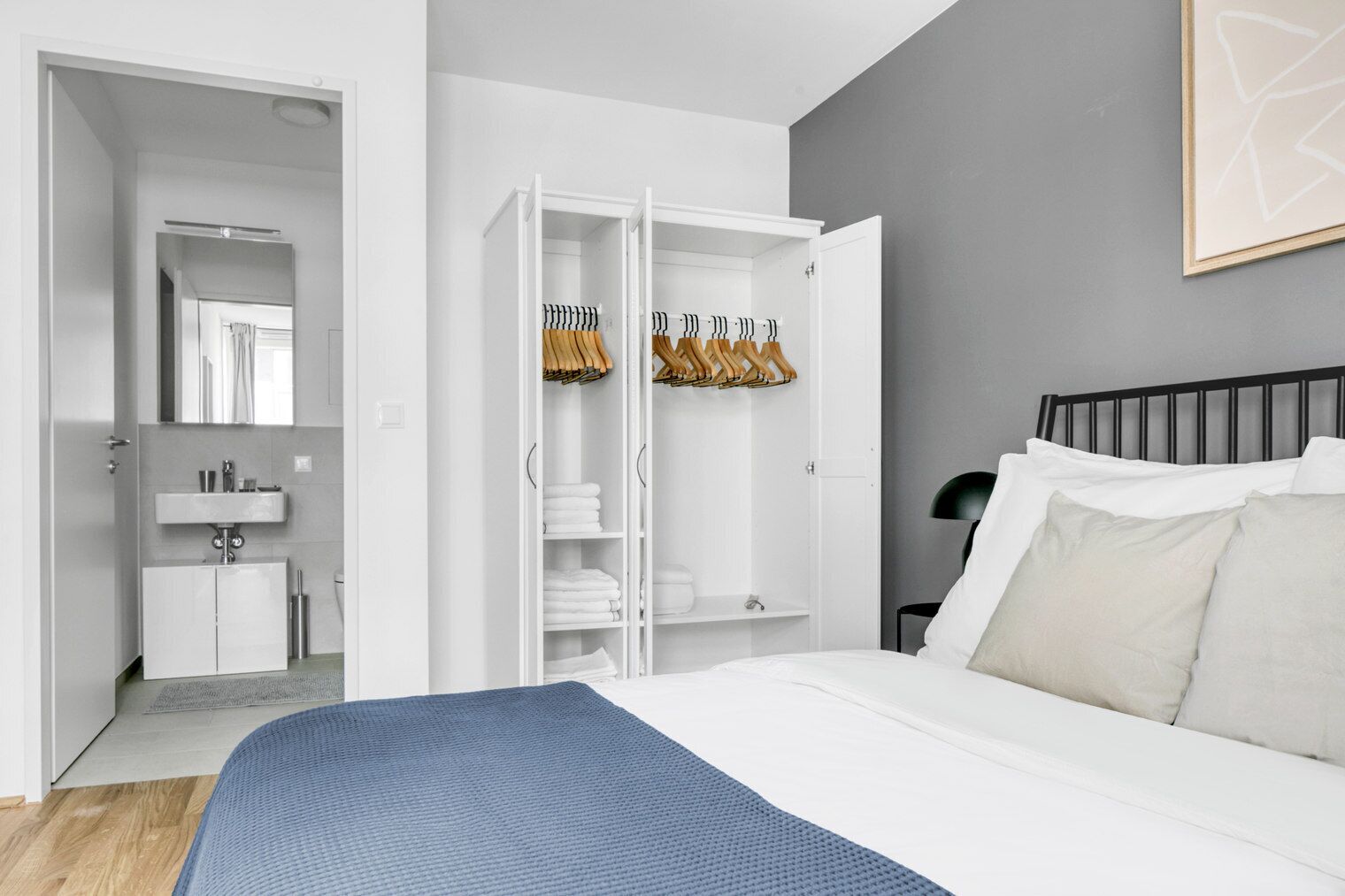 A modern bedroom with a bed, a wardrobe, and a bathroom.