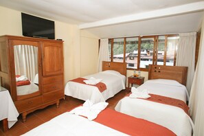 Habitación de hotel con dos camas, un armario de madera, un televisor y una ventana con vistas a edificios.