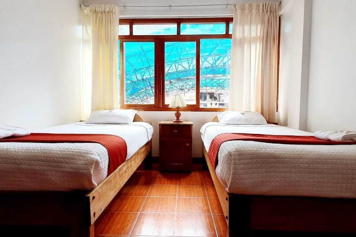 A room with two beds, a window with a view of a bridge, and a wooden floor.