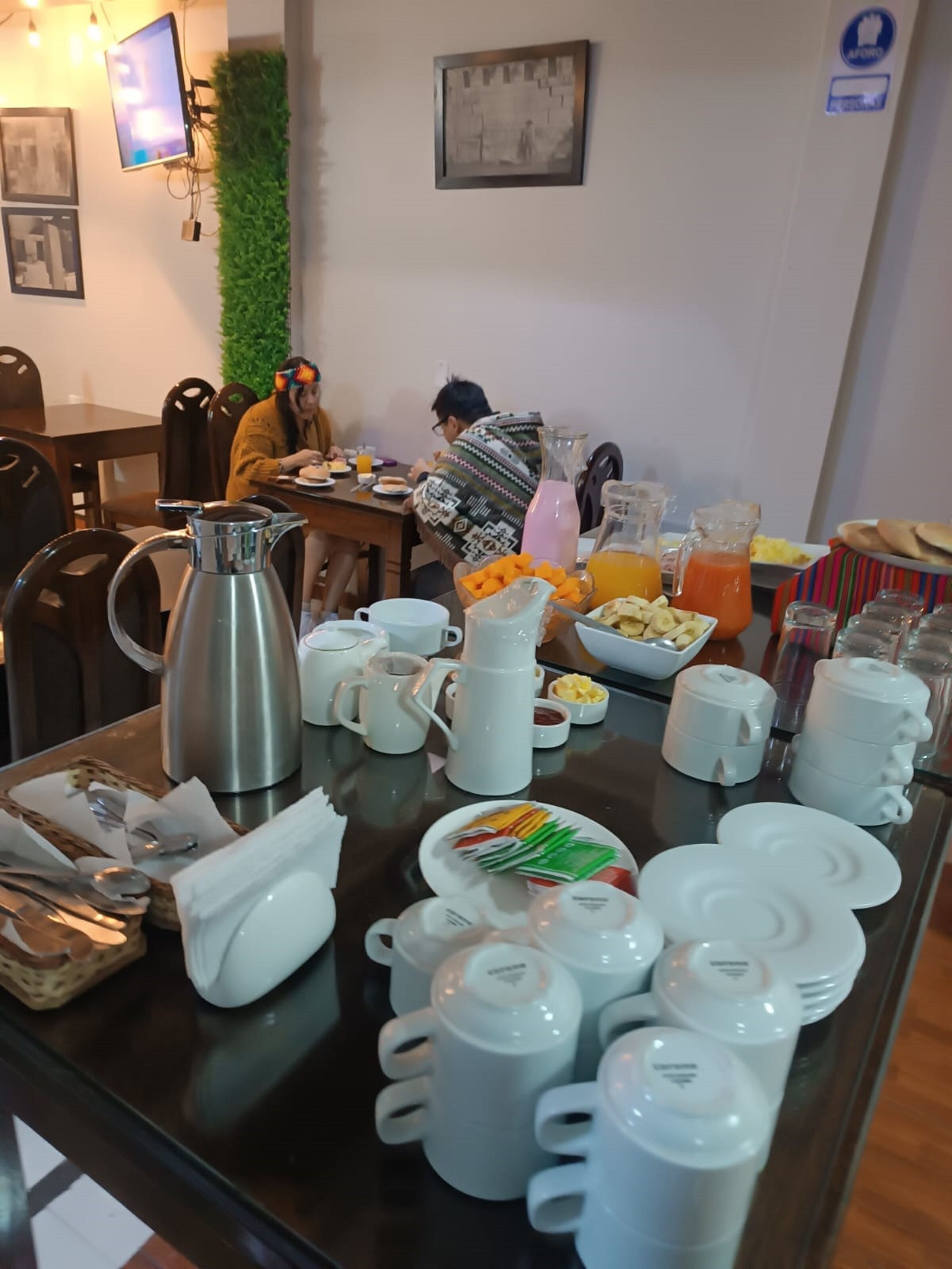 A breakfast buffet with various food items and beverages, including a coffee pot, teapots, and a fruit bowl.