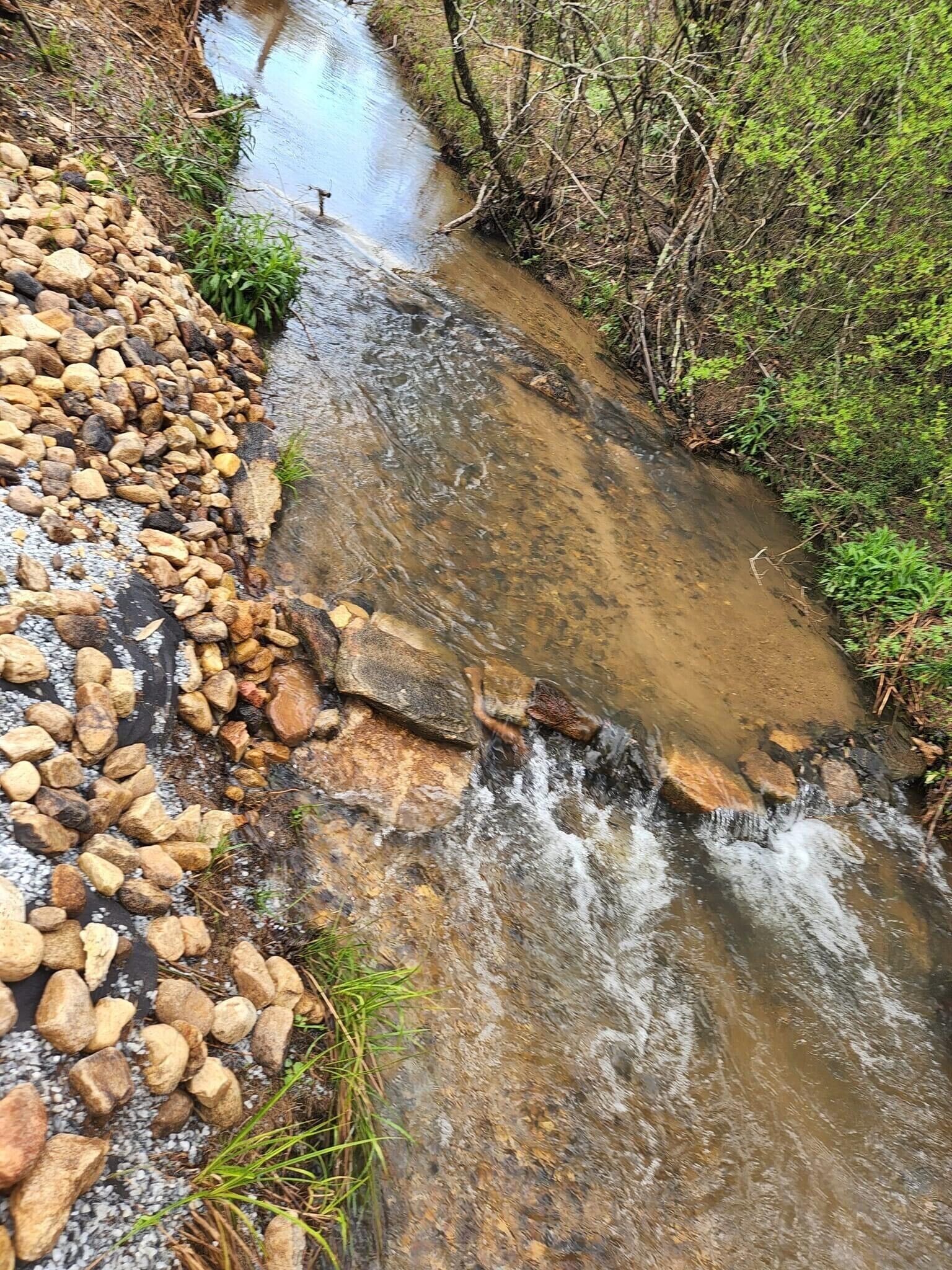 A small stream flowing over rocks in a wooded area.