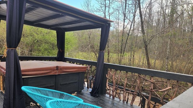 A covered outdoor deck with a brown bench and two turquoise chairs. - Lazy Bear Retreat by the Creek  (Pickens)