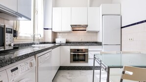 A modern kitchen with white cabinets, a built-in oven, a microwave, and a dishwasher. - Garcia de Vinuesa Atico by Home at Homes (Sevilla)