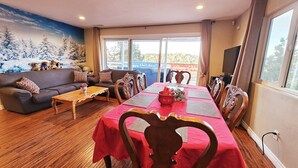 Sala de estar mobiliada com sofá, mesa de centro e mesa de jantar posta para quatro pessoas.